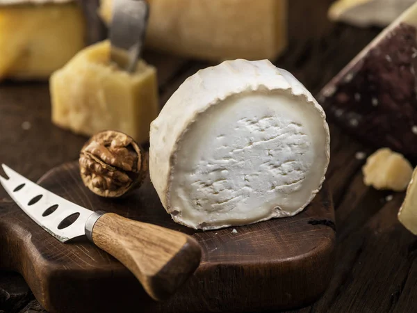 Slice of fresh goat cheese on wooden board. Cheese background. — Stock Photo, Image