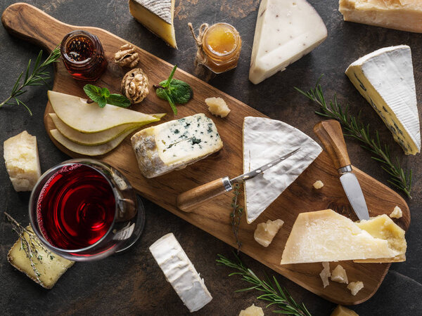 Cheese platter with different cheeses, fruits, nuts and wine on 
