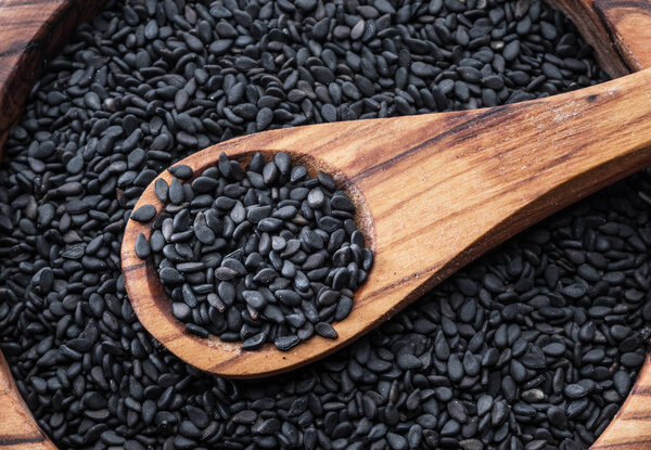 Black sesame seeds in the wooden spoon. Sesame seeds in the dish