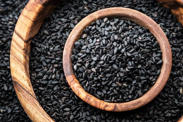 Black sesame seeds in the wooden bowl. Top view.