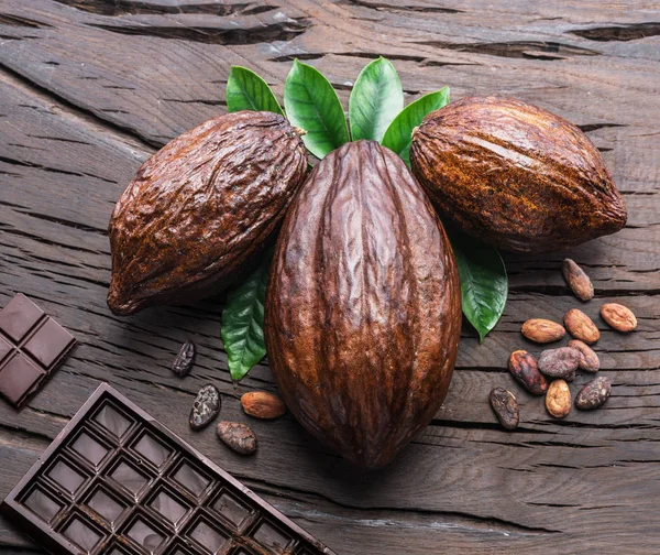 Cocoa pod, cocoa beans and chocolate on the wooden table. Top vi — Stock Photo, Image