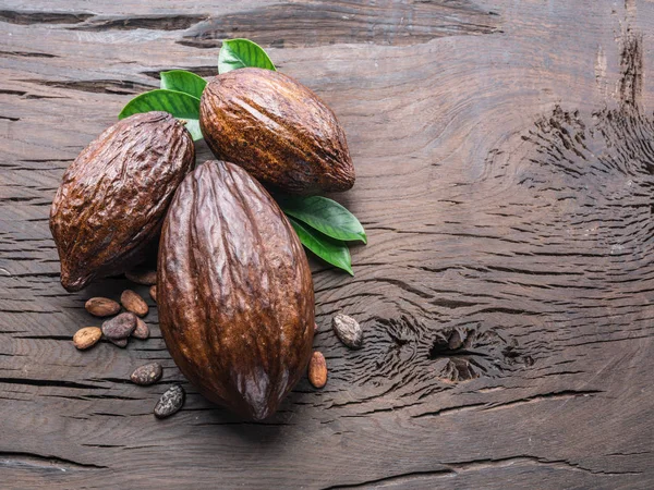 Kakaoschote und Kakaobohnen auf dem Holztisch. Ansicht von oben. — Stockfoto