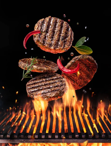 Carne de res molida en hamburguesa con especias vuelan sobre la llama g —  Fotos de Stock