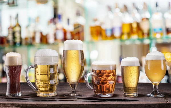 Cold mugs and glasses of beer on the old wooden table. Pub inter — Stock Photo, Image