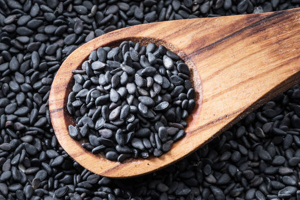 Black sesame seeds in the wooden spoon. Sesame seeds in the dish