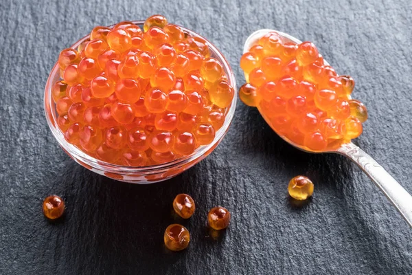 Caviar rojo en el tazón sobre fondo de grafito gris . — Foto de Stock