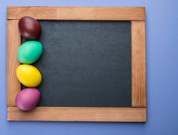 Tableau noir et oeufs de Pâques colorés autour d'elle. Vue d'en haut . — Photo