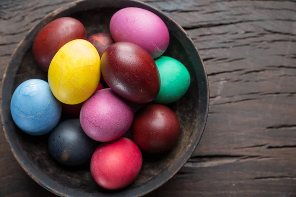 Colorful Easter eggs in bowl on wooden table. Attribute of Easte — Stock Photo, Image