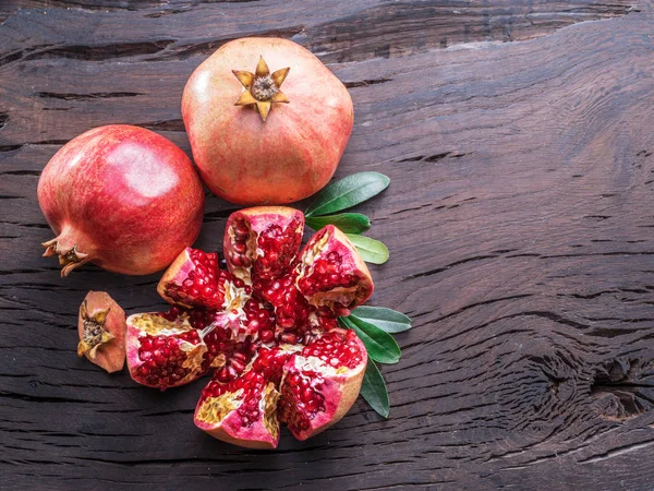 Rijpe granaatappel vruchten op houten tafel geopend. Bovenaanzicht. — Stockfoto