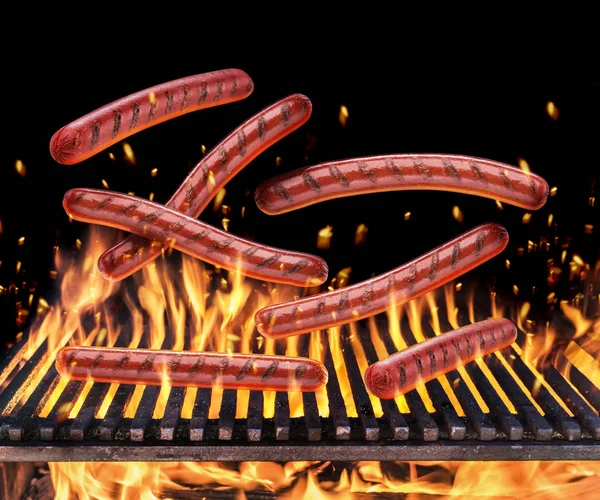 Enchidos que caem na grelha em chamas e línguas de fogo — Fotografia de Stock