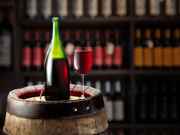 Botella de vino y copa de vino tinto en barrica de madera. Estantes de vino a —  Fotos de Stock
