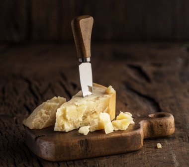 Parmesan peyniri ve peynir bıçağını ahşap tahta üzerinde parçası. D