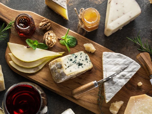 Bandeja de queso con diferentes quesos, frutas, frutos secos y vino en — Foto de Stock