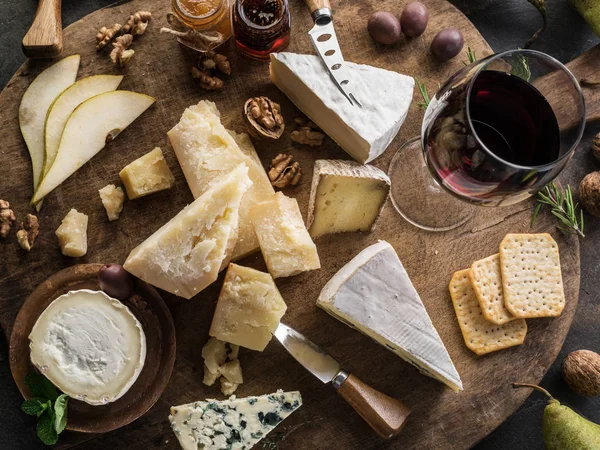 Bandeja de queso con diferentes quesos, frutas, frutos secos y vino en —  Fotos de Stock
