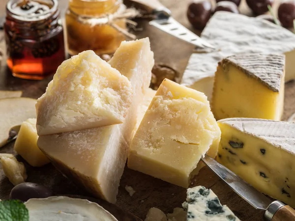 Kawałek parmezanu i asortyment różnych serów o — Zdjęcie stockowe