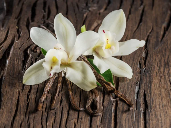 Getrocknete Vanillestäbchen und Vanille-Orchidee auf Holztisch. — Stockfoto