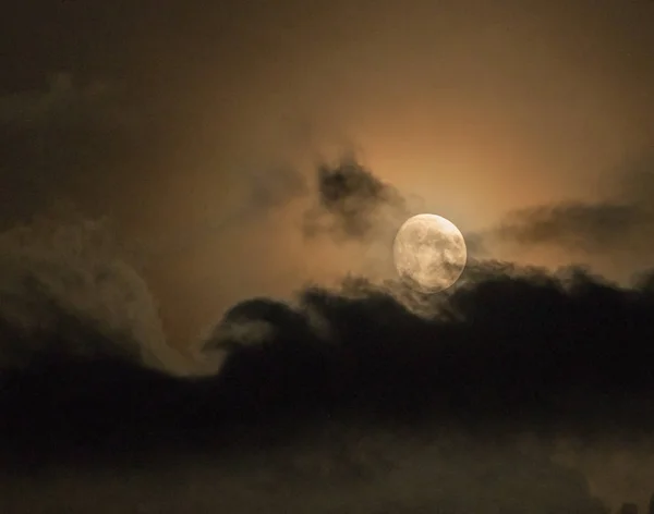 Yellow moon between heavy clouds in the night sky. — Stock Photo, Image