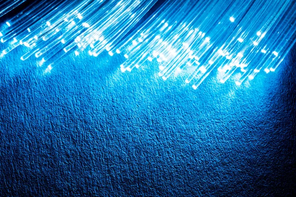Pacote de fibras ópticas com luzes nas extremidades. Fundo azul — Fotografia de Stock