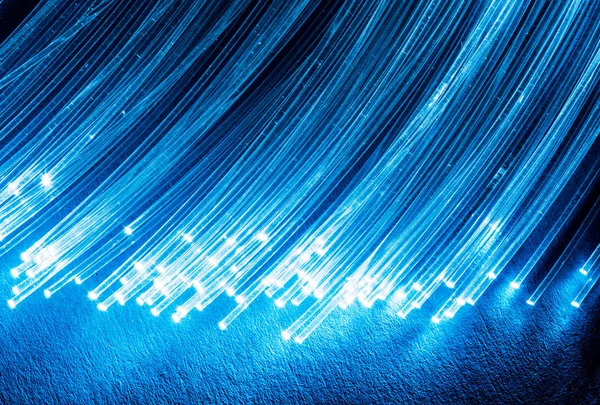 Bundle of optical fibers with lights in the ends. Blue backgroun — Stock Photo, Image