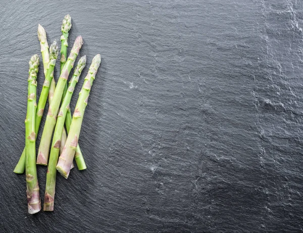 Germogli di asparagi giovani verdi sullo sfondo nero . — Foto Stock