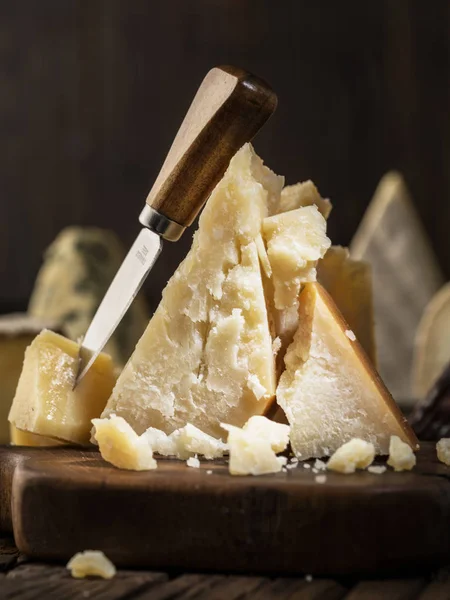 Pièce de fromage parmesan et couteau à fromage sur la planche en bois. D — Photo