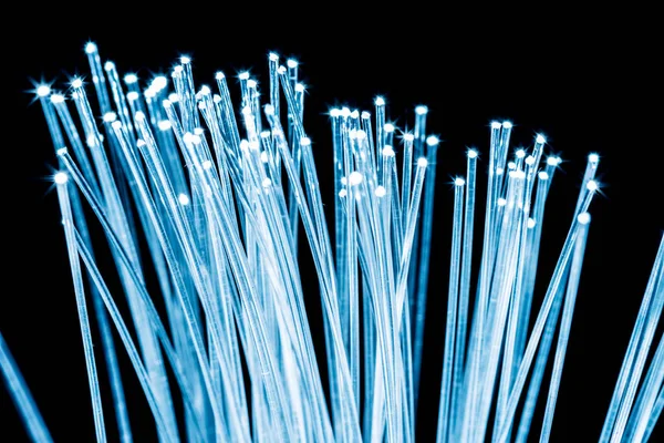 Bundle of optical fibers with blue light. Black background. — Stock Photo, Image