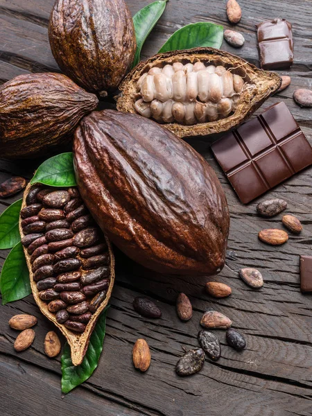 Cocoa pod, cocoa beans and chocolate on the wooden table. Top vi — Stock Photo, Image
