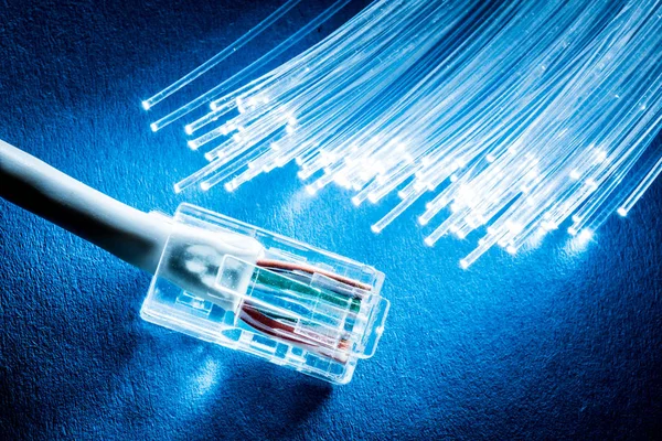 Cabo de rede e fibras ópticas com luzes no fundo azul . — Fotografia de Stock