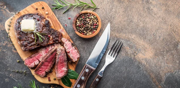 Bife Ribeye médio raro com ervas e um pedaço de manteiga no — Fotografia de Stock