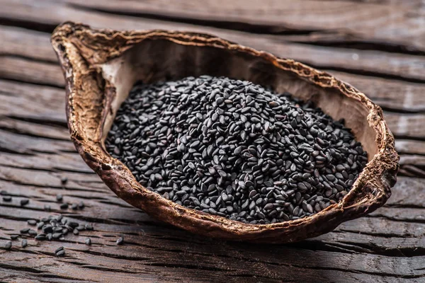 Black sesame seeds in the organic bowl on old wooden table. — Stock Photo, Image