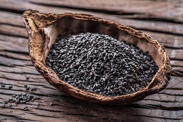 Black sesame seeds in the organic bowl on old wooden table. 
