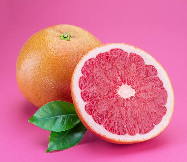 Grapefruit and grapefruit slice isolated on pink background.