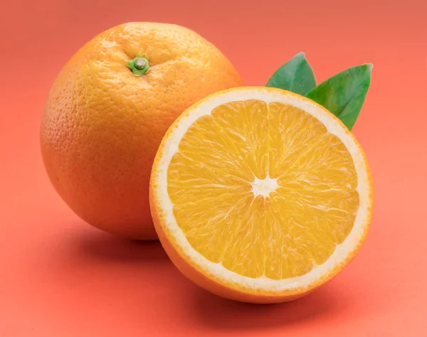 Orange fruit with orange slices and leaves isolated on orange ba