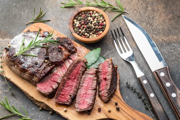 Bistec Ribeye medio raro con hierbas y un trozo de mantequilla en el —  Fotos de Stock