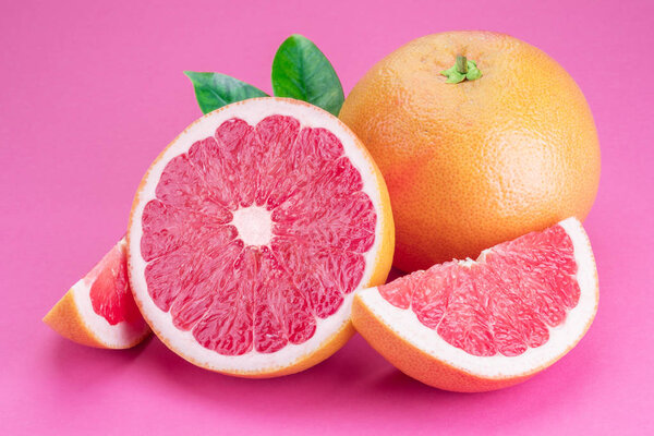 Grapefruit and grapefruit slices isolated on pink background.