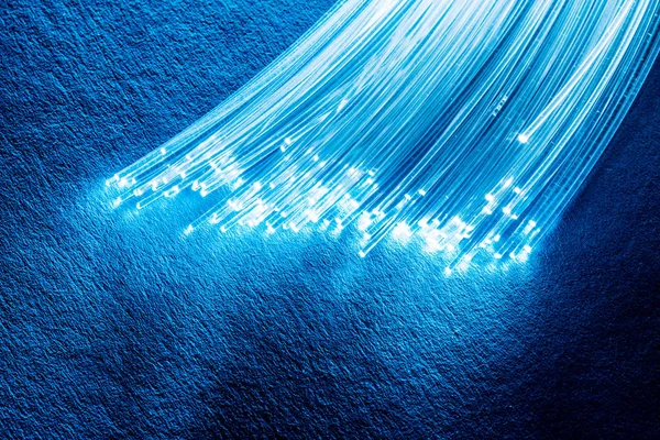 Bundle of optical fibers with lights in the ends. Blue backgroun