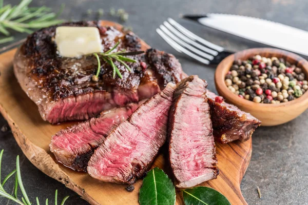 Steak Ribeye langka sedang dengan herbal dan sepotong mentega di — Stok Foto