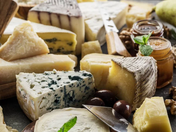 Surtido de diferentes quesos con aceitunas y mermeladas. Respaldo alimenticio — Foto de Stock