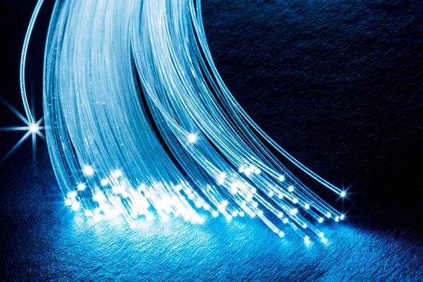 Bundle of optical fibers with lights in the ends. Blue backgroun — Stock Photo, Image