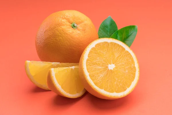 Orange fruit with orange slices and leaves isolated on orange ba