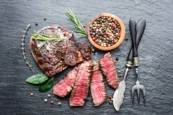 Medium rare Ribeye Steak mit Kräutern auf Graphitplatte. — Stockfoto