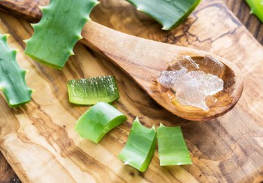 Taze aloe bırakır ve aloe jeli masada tahta kaşık içinde.