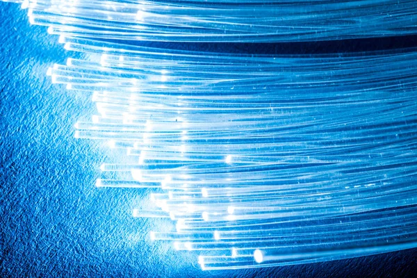 З'єднання оптичних волокон з вогнями на кінцях. Блакитний фон — стокове фото