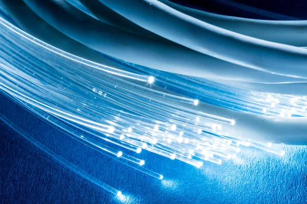 Cables de red y fibras ópticas con luz sobre fondo azul . — Foto de Stock