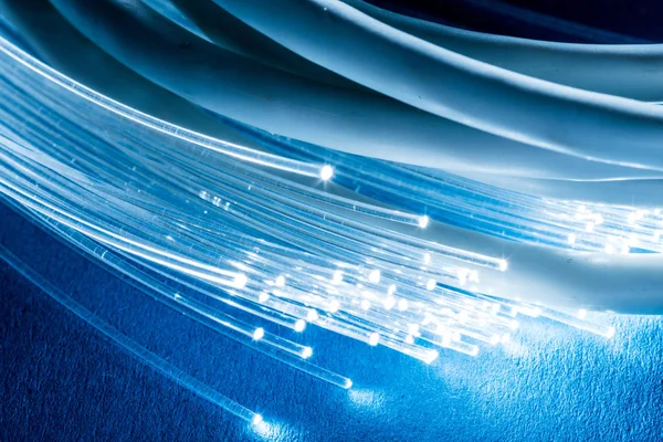 Network cables and optical fibers with light on blue background. — Stock Photo, Image