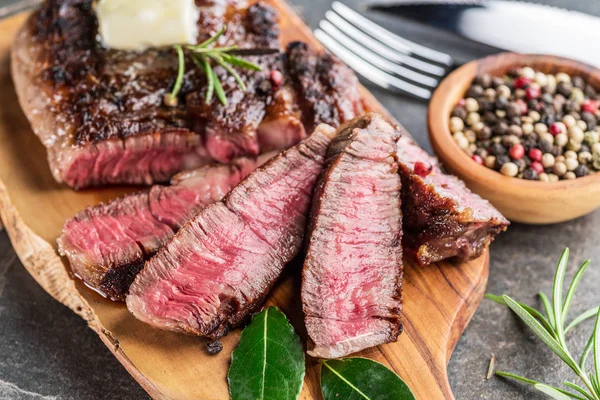 Steak de Ribeye moyen et rare avec des herbes et un morceau de beurre sur le — Photo