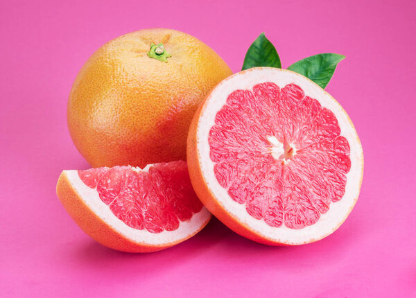 Grapefruits and grapefruit slices isolated on pink background.