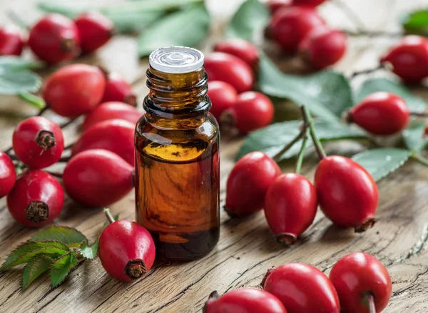 Hagebutten und Hagebuttenkernöl auf dem Holztisch. — Stockfoto