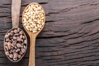 Tahta masadaki kaşıklarda çam fıstığı. Organik gıda.