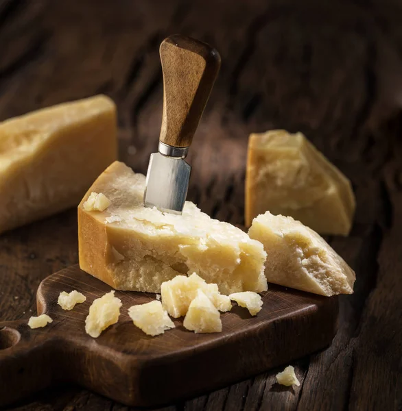 Piece of Parmesan cheese and cheese knife on the wooden board. D — Stock Photo, Image